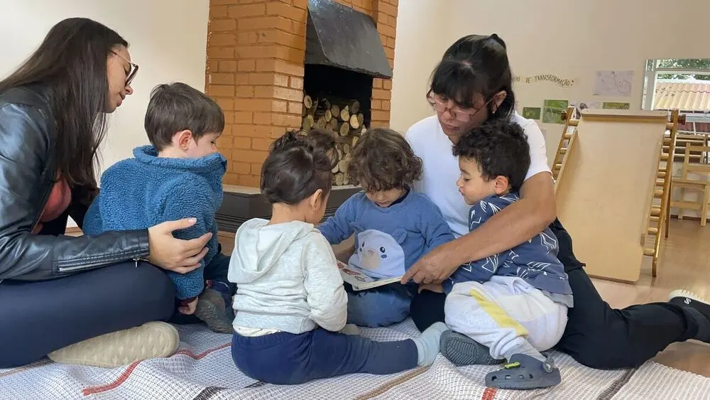 Grupo de crianças reunido perto da lareira ouvindo uma história no Espaço Santa Gianna